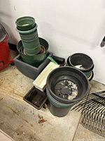 Various stacked green round pots, black/green pots, trays and planters