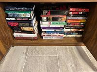 Full view of bottom shelf showing three stacks of assorted fiction and mystery books