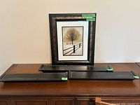 Three black wall shelves and framed wall art displayed on a sideboard