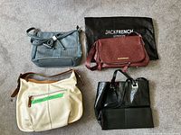 All four bags laid out: teal crossbody, burgundy crossbody, cream hobo, black tote