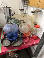 Group view of assorted feeders: blue hummingbird, green mesh, clear tube, black mesh, red parts