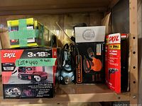Shelf with boxed SKIL belt sander, Black+Decker orbit sander, SKIL drill, Ryobi sander box and loose vintage drill