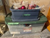 Two stacked plastic totes containing assorted Christmas decorations