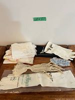 Overview of all items on tray: handkerchiefs stack, ivory gloves, blue garter, mesh accessory, packaged Geo. Morgan gloves