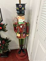 Full view of multicolor metal nutcracker statue on red base