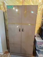 Front view of closed brown/taupe metal cabinet showing two doors and handles