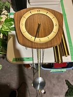 Front view of wall clock with pendulum, chains and weights visible