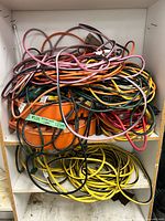 Overall view of mixed colored extension cords piled on shelving with cord reels visible