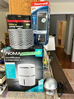 Group shot showing NOMA humidifier box, Honeywell tower fan box, Honeywell pre-filter pack, two silver tabletop diffusers