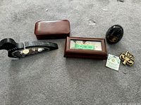 All items laid out: wood jewelry box, leatherette case, wooden loon coin bank, marble egg bank, brass plaque, brass pin, small ring