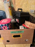 Overall view of cardboard box, toolbox, large cable tie pack, floral tin, wicker basket
