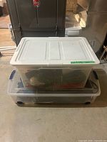 Two stacked clear plastic bins containing cords and devices