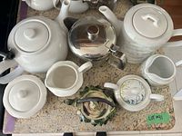 assortment of teapots, kettle, sugar bowl and creamers on countertop