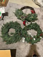 Three artificial wreaths on floor showing overall contents