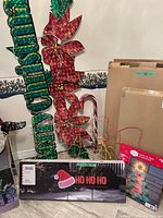 Group view showing Merry Christmas sign, poinsettias, candy cane, boxed HO HO HO sign, boxed tree silhouette and wire frames