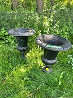 Full view of both black cast iron urns in grass