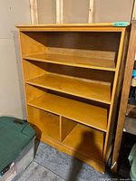 Front view of light honey plywood bookcase with four shelves and two lower cubbies