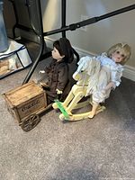 Dolls seated with wagon and rocking horse visible