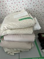 Stacked bedding pieces showing patterned duvet cover and solid sheets