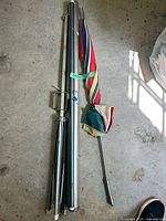 Collapsed screen components, carrying tube, striped umbrella on floor