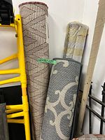 Three rolled Safavieh area rugs standing upright