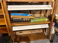 Front view of shelf with grow lights, boxed greenhouse kits, seed trays visible