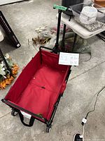Top view of red fabric utility wagon unfolded with handle extended and manual visible