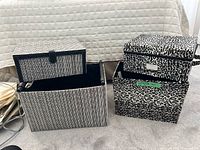 Four decorative fabric-covered storage boxes grouped on carpet, showing relative sizes