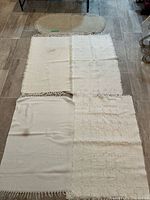 Group shot showing four rectangular white/cream cotton rugs and one oval runner laid out on tiled floor