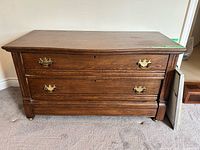 Front view showing two drawers, brass pulls, keyholes, casters