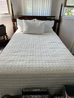 Bed fully made showing wood frame, quilt, pillows