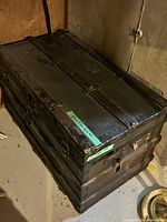 Top and side view of closed steamer trunk showing ribbed metal trim and wear