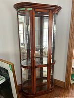 Full view of brown wood curio cabinet with glass sides and door