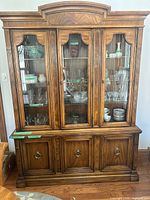 Full view of china cabinet showing wood finish, glass doors and upper crown