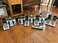 Full set of 9 VTech cordless handsets lined up with charging bases and adapters visible on floor