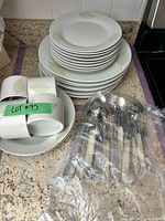 Stacked plates, bowls, mugs, wrapped flatware