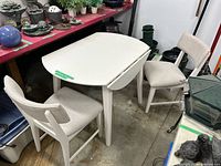 Overall view of white dining table with two upholstered chairs