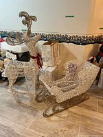 Assembled wire mesh reindeer beside boxed reindeer kits and assembled sleigh