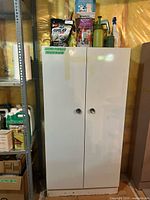 Front view of white metal storage cabinet with contents on top