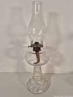 Full view of clear pressed glass oil lamp with chimney