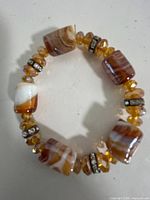 Top view of entire bracelet showing banded stones, amber beads, and rhinestone spacers