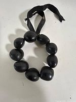 Top view of kukui nut bracelet showing nine polished black nuts and ribbon ties
