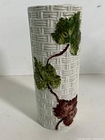 Full view of vase showing basket-weave texture and vine leaves