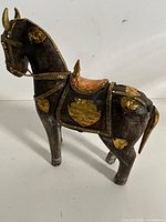 Full view left side of carved wooden Marwari horse with brass plaques and chain reins