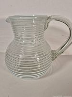 Full side view of clear glass pitcher with white spiral lines and handle