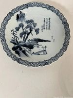 Front view of blue and white Japanese ceramic plate showing landscape and haiku, scalloped rim