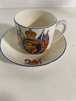 Teacup on saucer showing royal portrait and flag design