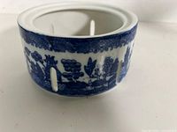 Blue and white ceramic tea light holder showing Blue Willow pattern and side slots