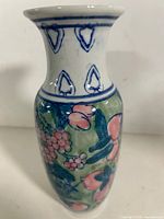 Front view of porcelain vase showing floral and berry design with blue accents on neck