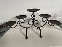 Front view of wrought iron candelabra showing five plates and scroll design